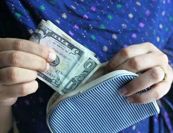 a han stuffing some cash into a wallet