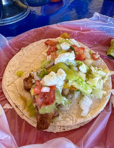 A drunken beer battered fish taco with guacamole, tomatoes, and lettuce on a Mazatlán food tour.