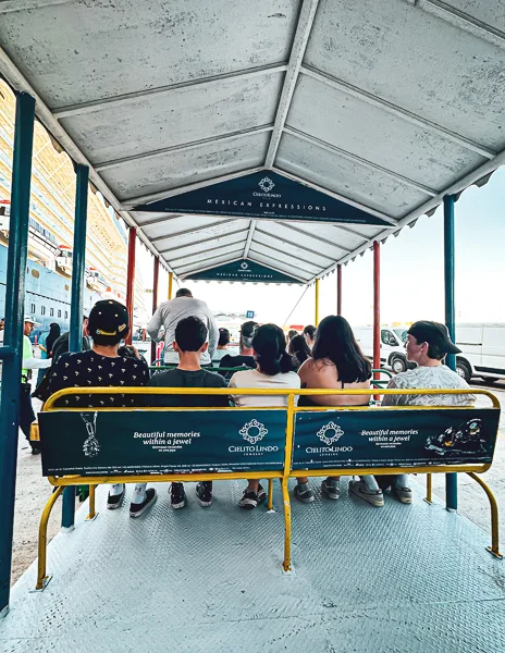 Passengers seated on a shuttle at the Mazatlán cruise port, preparing to head towards the cruise terminal.