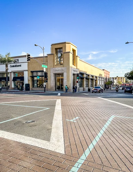 Street corner in Old Pasadena featuring a mix of retail stores, with a focus on the Tiffany’s building and nearby shops.