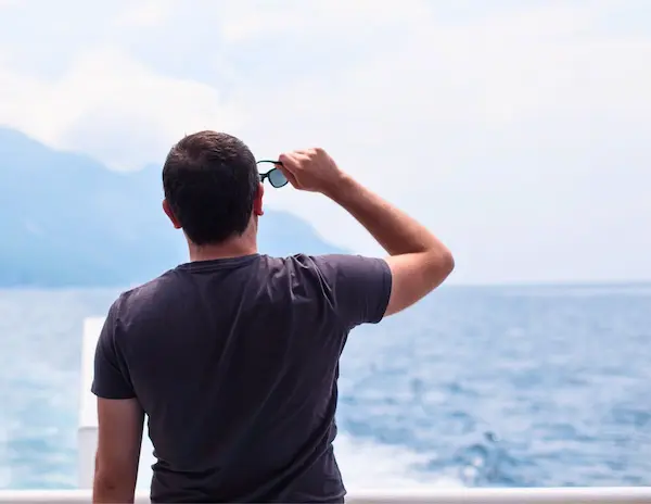 male cruise passenger wearing a t-shirt on a crusie ship looking out into the ocean