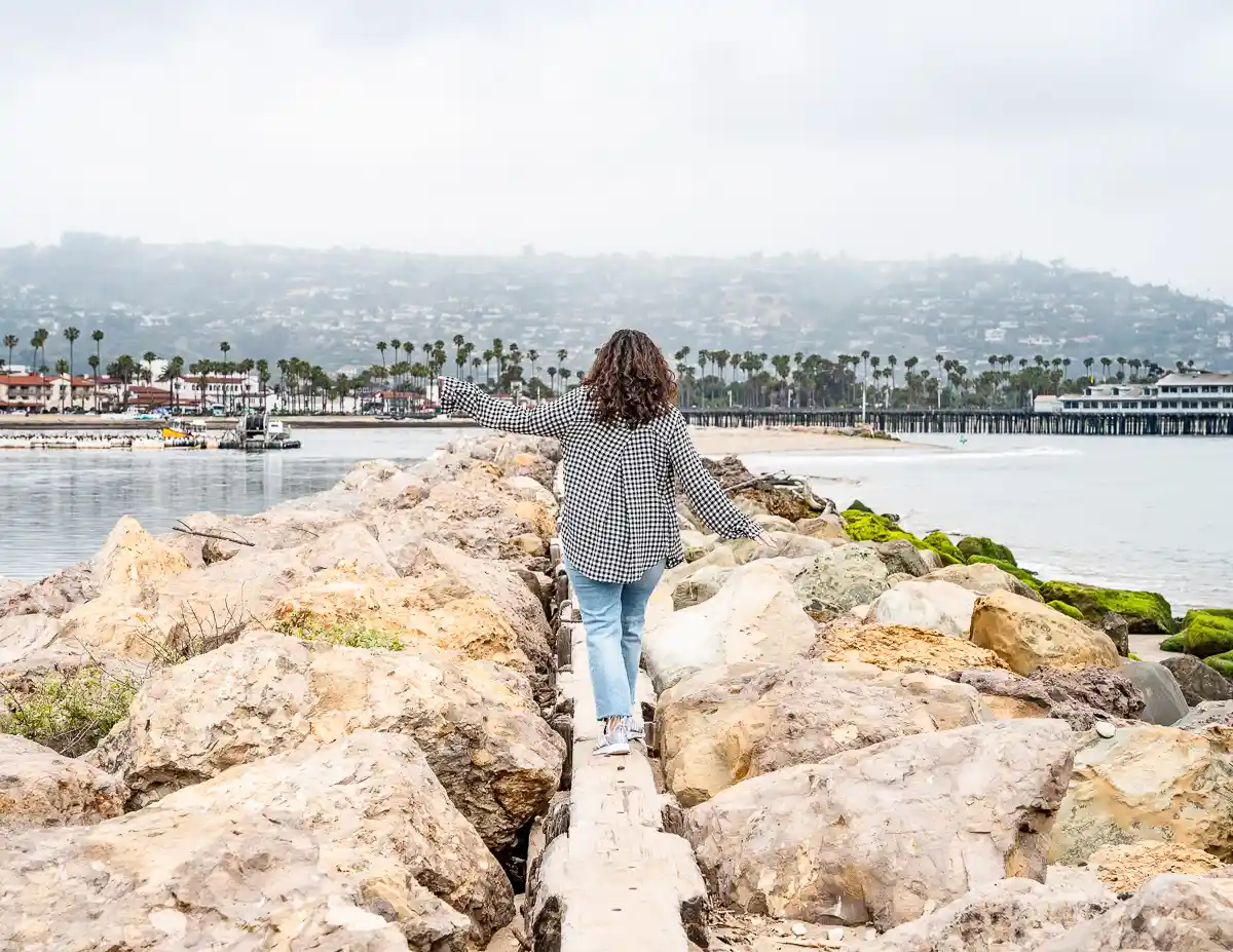 kathy walking and balancing along the wooden walkway along the rocky shore of point castillo