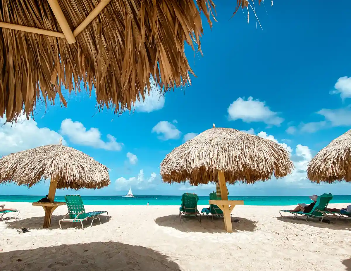 beach umbrellas and chairs on white sand beach facing the bluest water in aruba