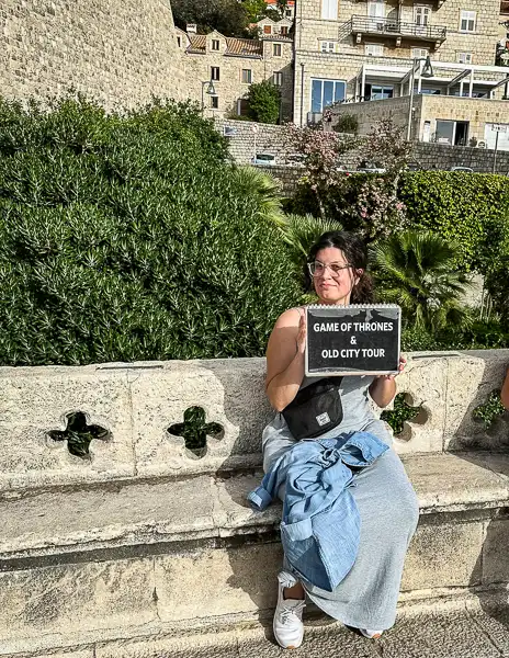 kathy holding a sign that says games of throne and old city tour sign in croatia