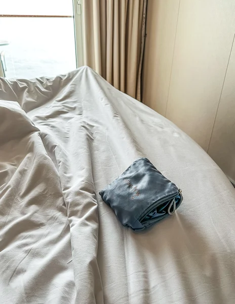 closed laundry bag sitting on the bed in a cruise cabin