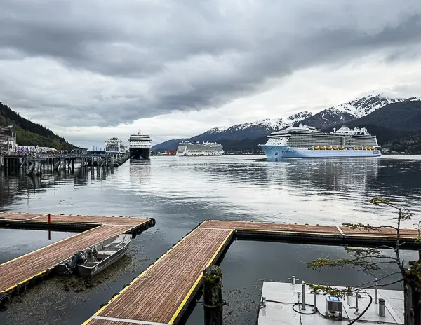 Cruise ships docked in Juneau, Alaska, surrounded by misty mountains and calm water on an overcast day