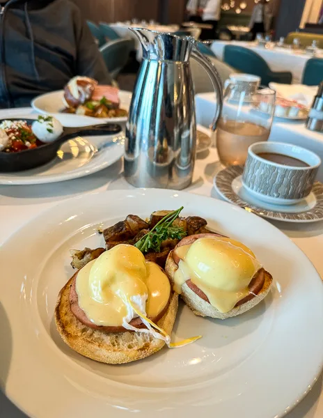 eggs benedict serviced with coffee and a full spread on table on the norwegian encore