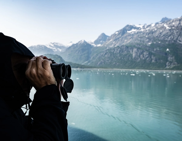 man using binocular on alaska cruise