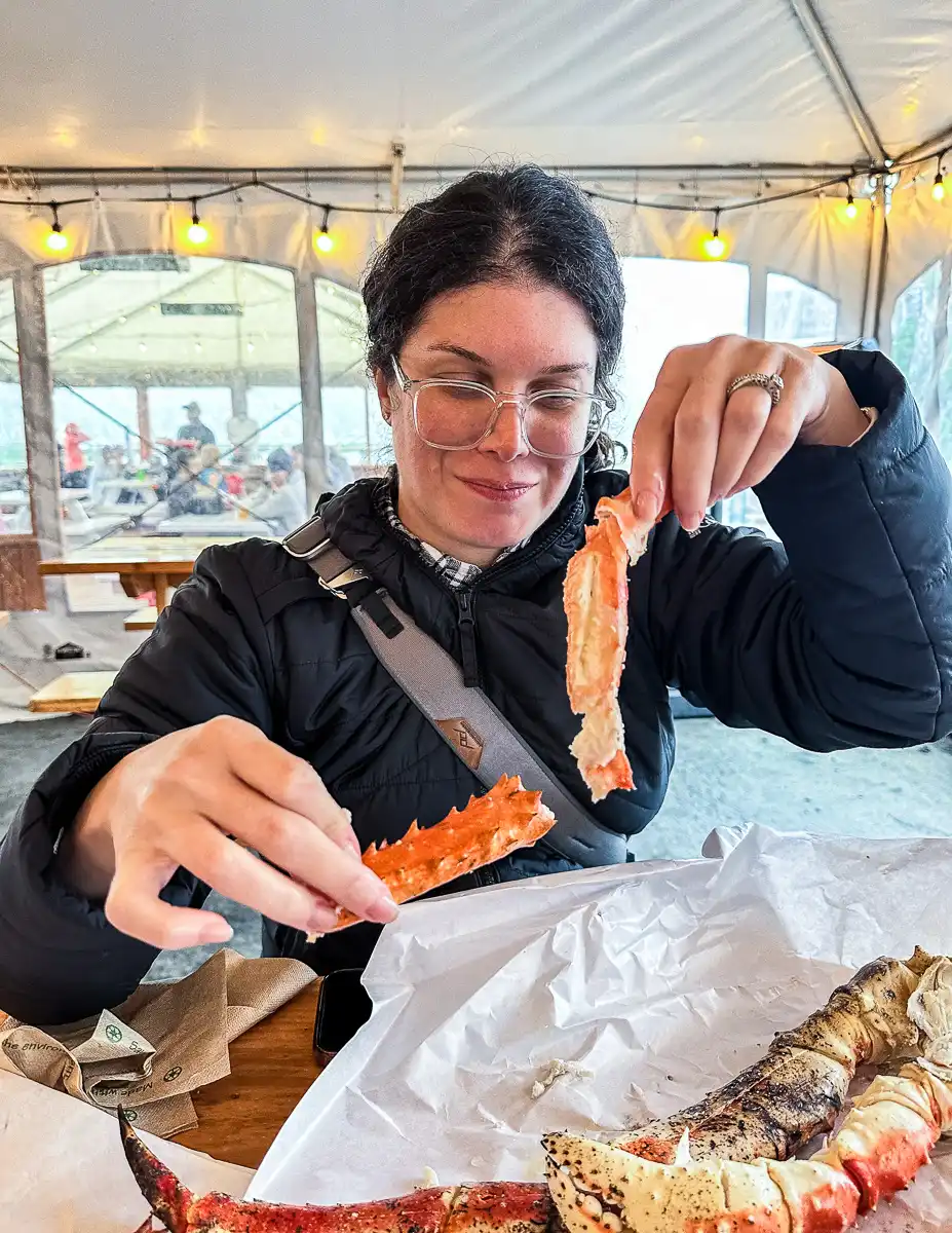 enjoying freshly cracked king crab legs at Tracy's King Crab Shack, with a focused expression as she savors the flavor.