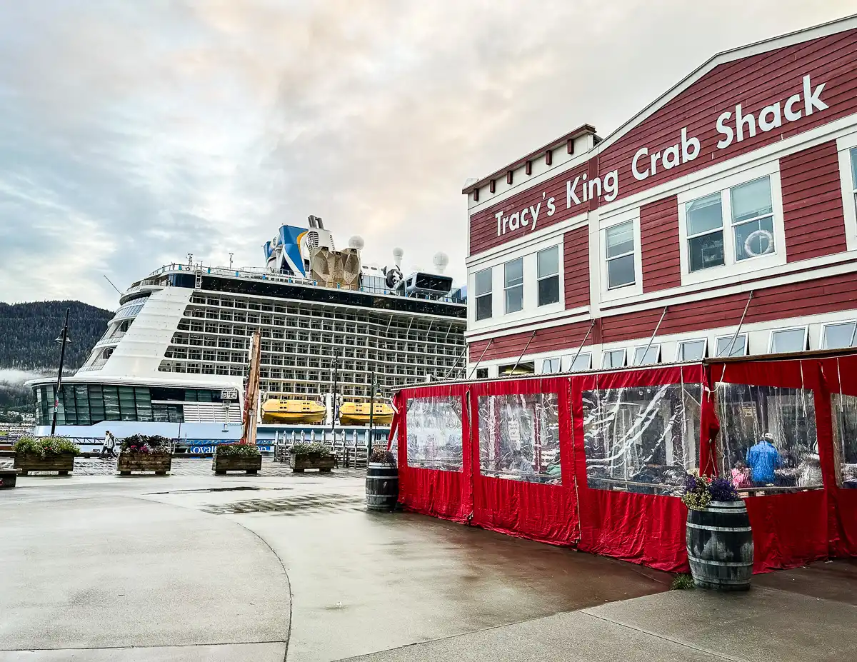 Exterior view of Tracy’s King Crab Shack located near the cruise port with the cruise ship docked in the background, highlighting the proximity to the waterfront.