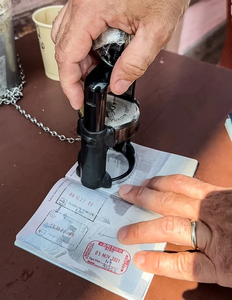 Close-up of a person's hands stamping a passport with a 'Yukon' seal, showcasing various travel stamps already in the passport, capturing the moment of adding a new destination to their travel documentation.