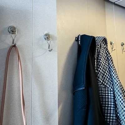 magnetic hooks on the walls of a cruise cabin holding a purse and sweaters
