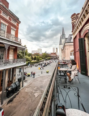 kathy sitting on balcony of meriels in new orleans overlooking jackson square