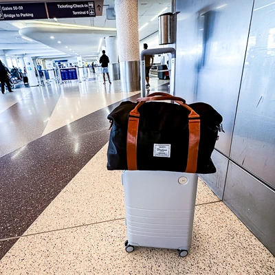 versaltille carry on bag from amazon in black sitting atop of a carryon luggage