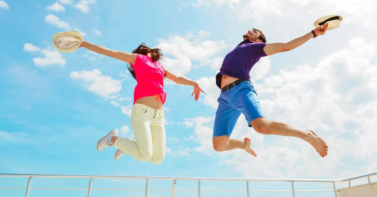 featured blog image without text | cruise memes and cruise jokes | couple excitedly jumping high on cruise ship deck