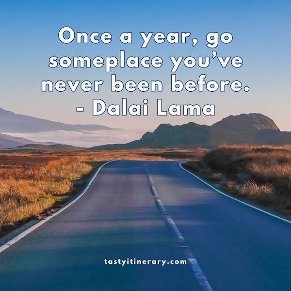 graphic for dalai lama quote, a picture of an open road with the text "Once a year, go someplace you’ve never been before."