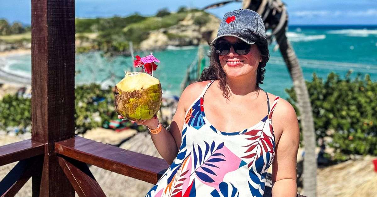 featurd blog image without text of kathy enjoying a day at port in the caribbean holding a coconut \ what to pack for a caribbean cruise