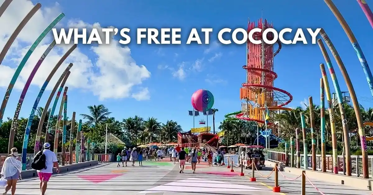 featured blog image: Cruise passengers walking along a colorful pier at CocoCay with waterslides and a balloon ride in the background, with overlay text “What’s Free at CocoCay.”