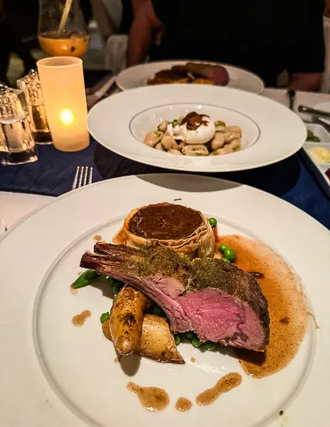 Herb-crusted lamb chops and gnocchi entrees at Blu on Celebrity Eclipse, beautifully plated.