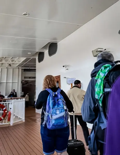 Cruise passengers boarding Norwegian Encore through the priority embarkation line marked for The Haven guests at the start of the cruise