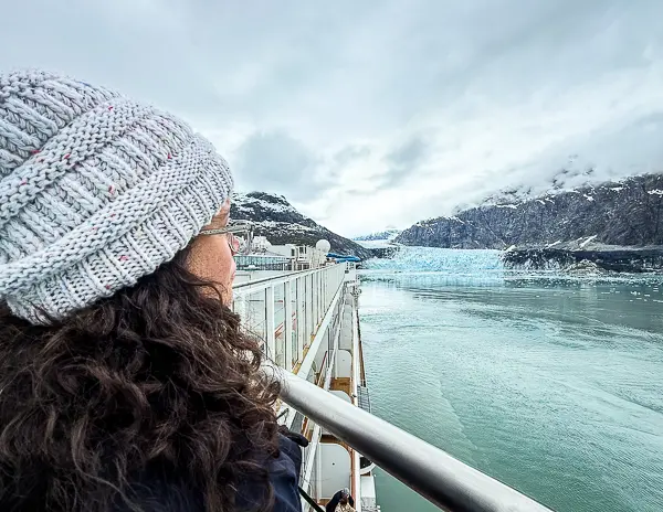 Woman (kathy)  in a knit hat looking out at Margerie Glacier from the deck of Norwegian Encore during an Alaska cruise through Glacier Bay