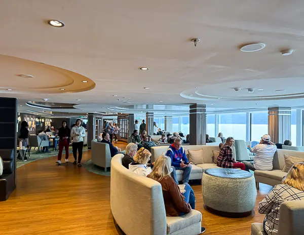 Crowded Observation Lounge on Norwegian Encore in 2025, showing guests seated in nearly every chair after the space was reduced during the 2024 dry dock.