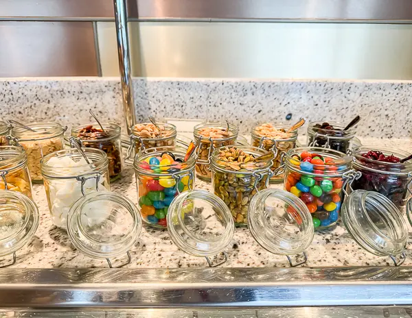 Selection of snacks in glass jars, including candy, nuts, and dried fruit, available in The Haven Observation Lounge on Norwegian Encore