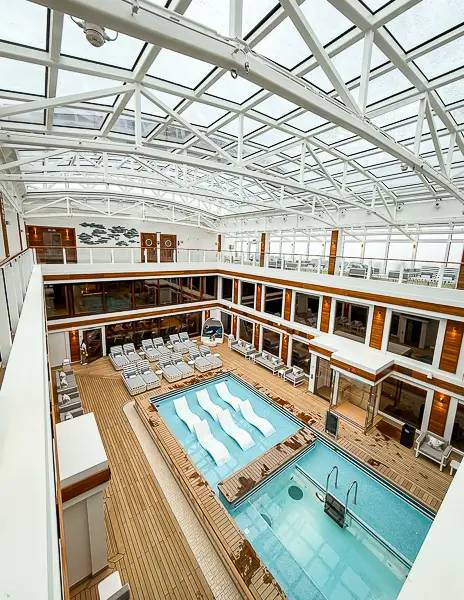 The Haven Courtyard on Norwegian Encore featuring a private pool, lounge chairs, and a retractable glass roof exclusive to Haven guests.