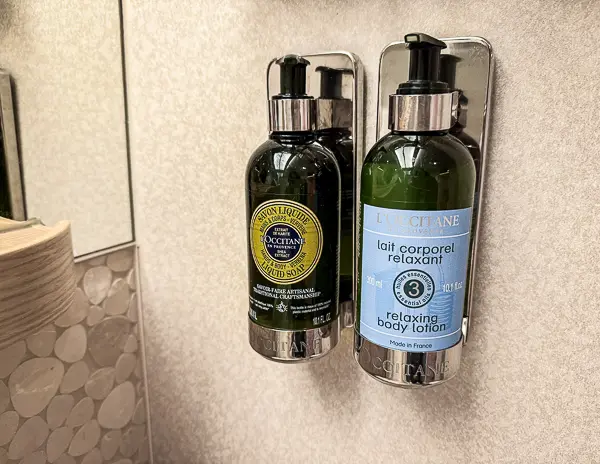 Close-up of L’Occitane soap and body lotion dispensers provided in The Haven bathroom on NCL Getaway.