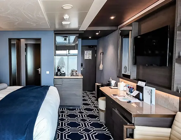 View of the NCL Encore Haven Penthouse Suite 17112 showing the bed, TV, vanity, and coffee station.