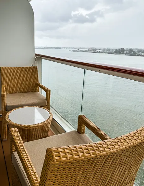 Side angle of The Haven Suite 14138 balcony setup on Norwegian Getaway, showing chairs and table with a view of the river.
