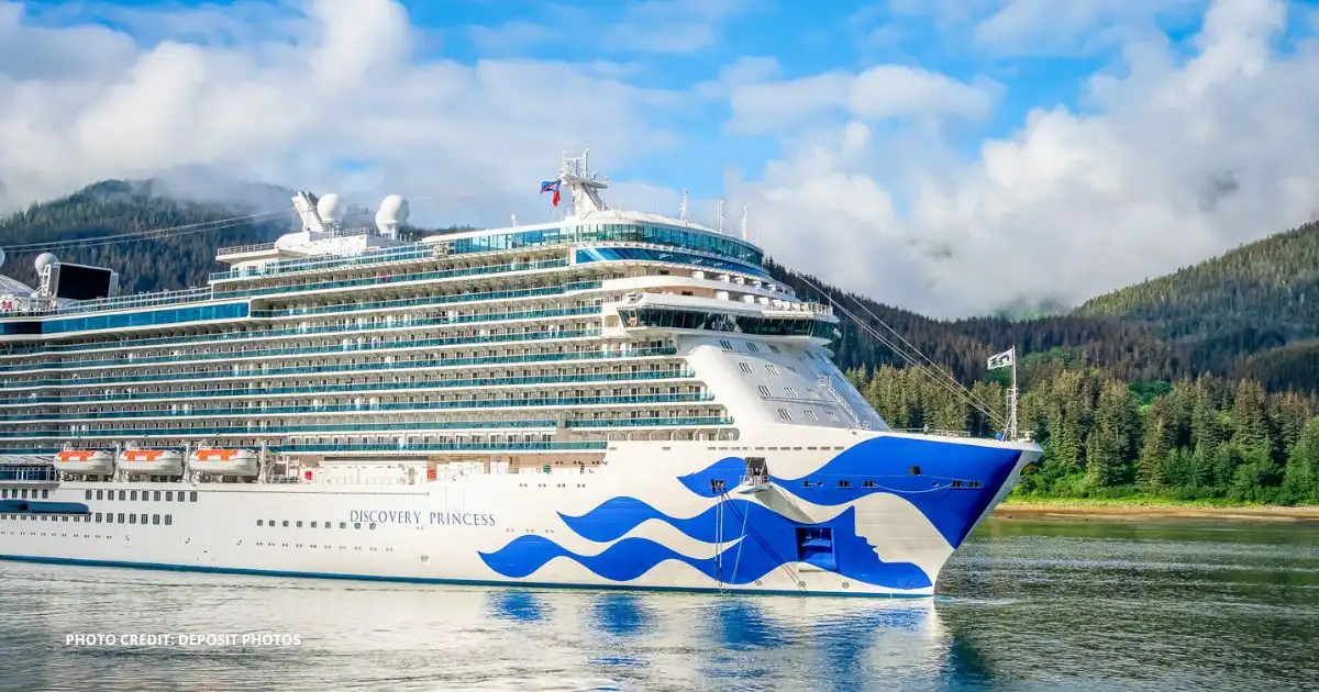 Discovery Princess cruise ship sailing in Alaska with mountains and forest in the background