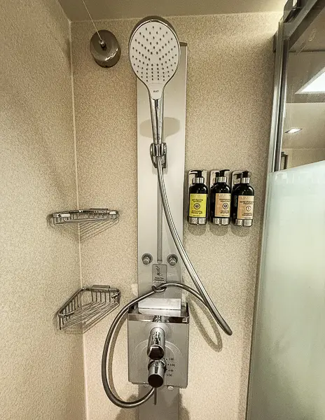 Massage shower head and mounted L'Occitane toiletries in The Haven Suite 14138 on Norwegian Getaway.