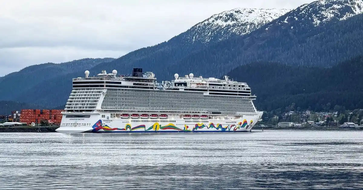 Norwegian Encore cruise ship docked in Alaska with snow-capped mountains in the background, illustrating our experience sailing Norwegian Encore to Alaska in The Haven.