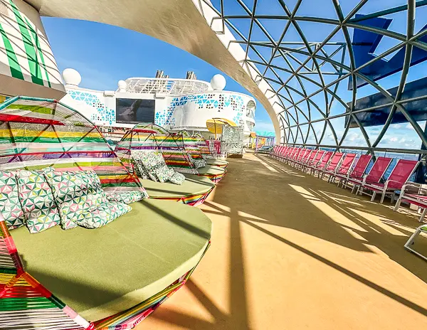 Colorful and spacious lounge area on a modern cruise ship, showing open seating and ocean views.