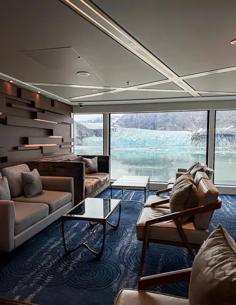 The Haven Observation Lounge aboard Norwegian Encore with comfortable seating and a view of Margerie Glacier through large panoramic windows during an Alaska cruise