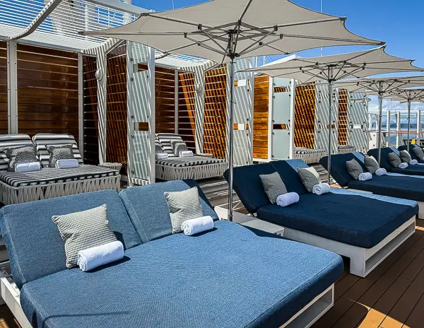 Loungers and daybeds with umbrellas on The Haven sundeck aboard Norwegian Encore on a sunny day