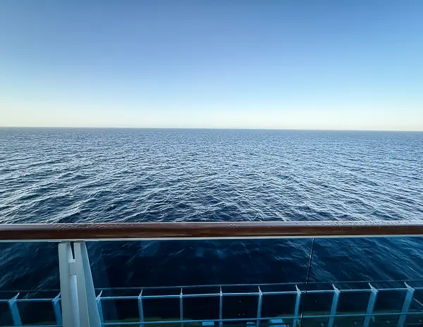 View of the open sea from the balcony of Carnival Firenze Ocean Suite 7359, framed by the railing
