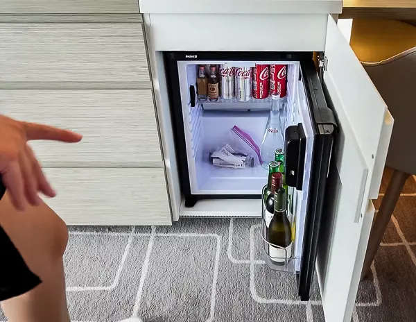 Cruise ship cabin mini-fridge with drinks and snacks stored inside, repurposed for personal use instead of the default minibar.