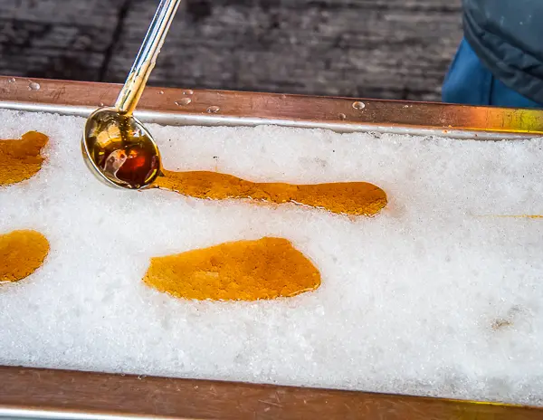 Hot maple syrup being poured onto fresh snow to make maple taffy