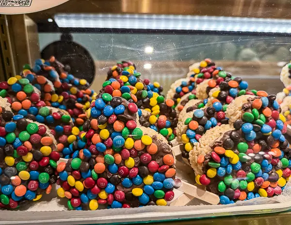 Mickey-shaped Rice Krispie treats at Disneyland, dipped in chocolate and coated with colorful M&M candies.