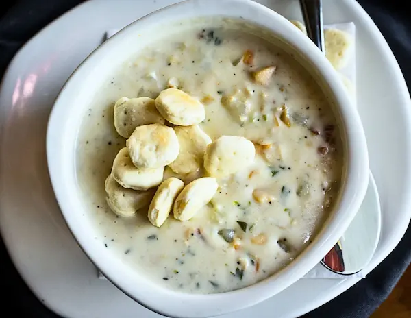 Bowl of New England clam chowder topped with oyster crackers, a classic fall comfort food in New England.