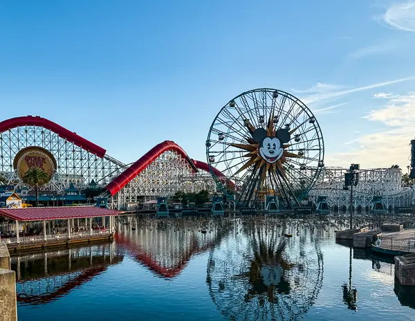 Pixar Pier at Disney California Adventure with the Incredicoaster and Pixar Pal-A-Round reflected in the water at sunrise.