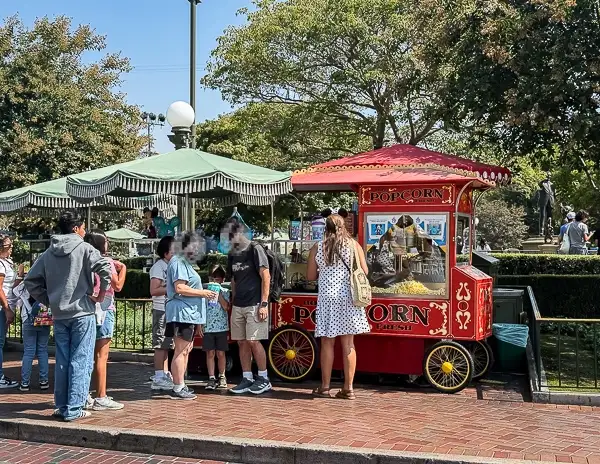 Popcorn cart at Disneyland with guests lined up to buy snacks.