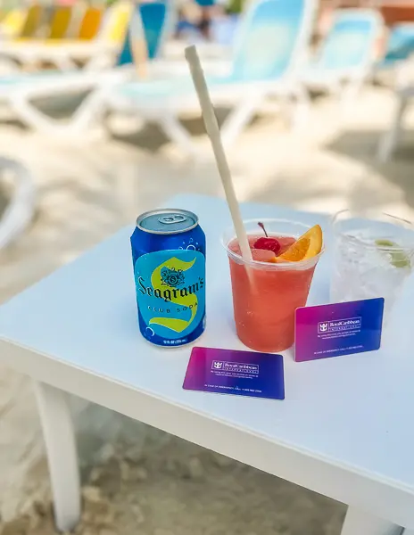 Coco Loco frozen cocktail served at Perfect Day at CocoCay with Royal Caribbean drink package, shown with soda, water, and SeaPass cards on a beach table.