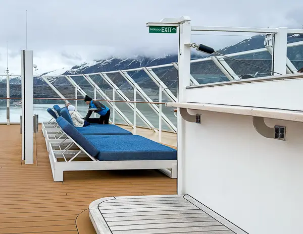 Cruise ship crew member helping passengers on deck, reflecting the hard work and kindness of the staff who make cruising enjoyable.
