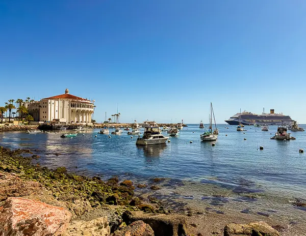 View of Avalon Bay from Casino Way, with the Catalina Casino on the left, boats in the harbor, and a cruise ship anchored offshore.