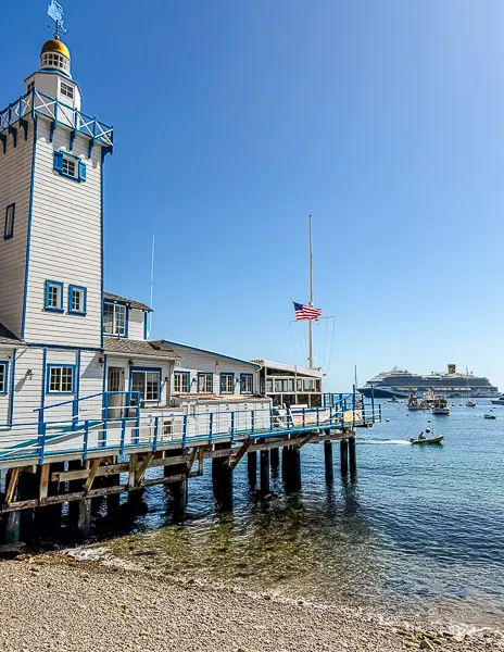 Catalina Island Yacht Club on Casino Way in Avalon, with boats in the harbor and a cruise ship anchored in the distance.