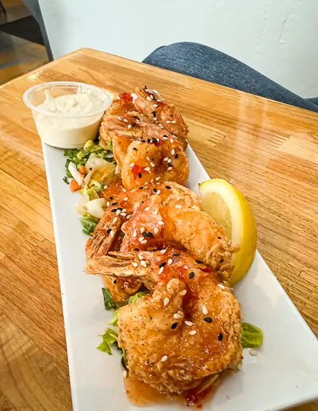 Plate of DaBomb shrimp topped with sesame seeds and sauce, served with lemon and dipping sauce at NDMK Fish House in Avalon, Catalina Island.