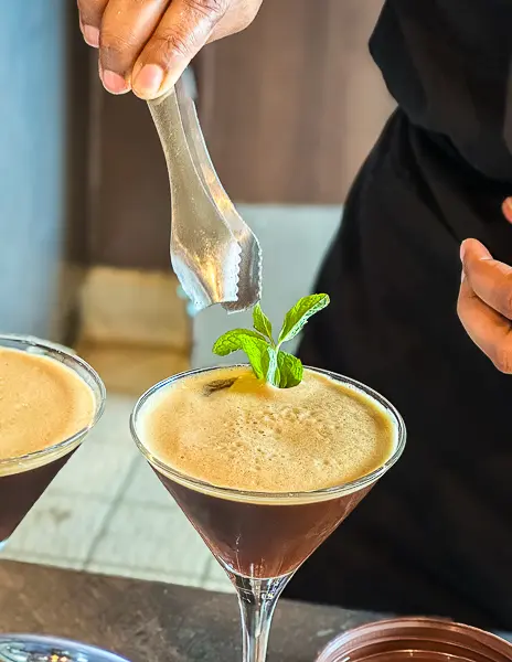 Bartender garnishing an espresso martini with fresh mint on a Celebrity Cruise ship.
